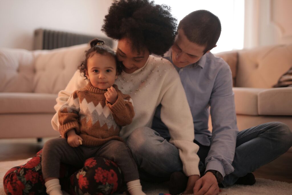 A joyful family of three sitting together, exuding warmth and happiness indoors.