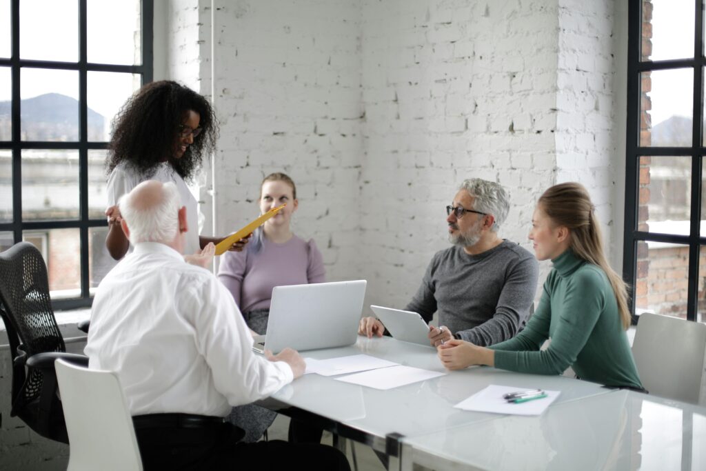 A team of diverse professionals discussing a project in a modern office setting with laptops and documents.